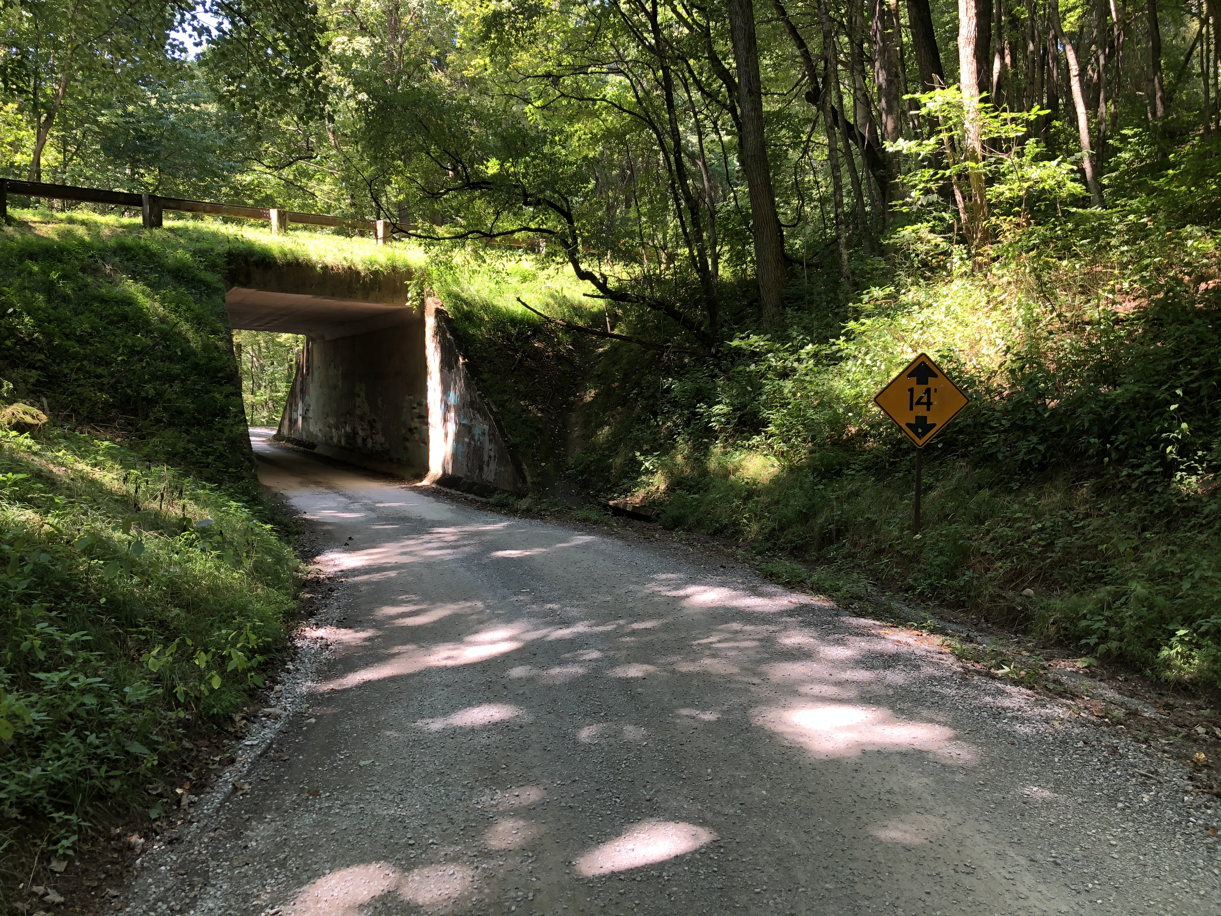The well-maintained gravel entry road passes under the Parkway and a portion of the Mountains-To-Sea trail runs along the road.