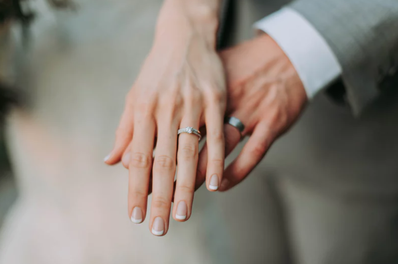 Hands of a bride and groom crossed, showing off wedding ring